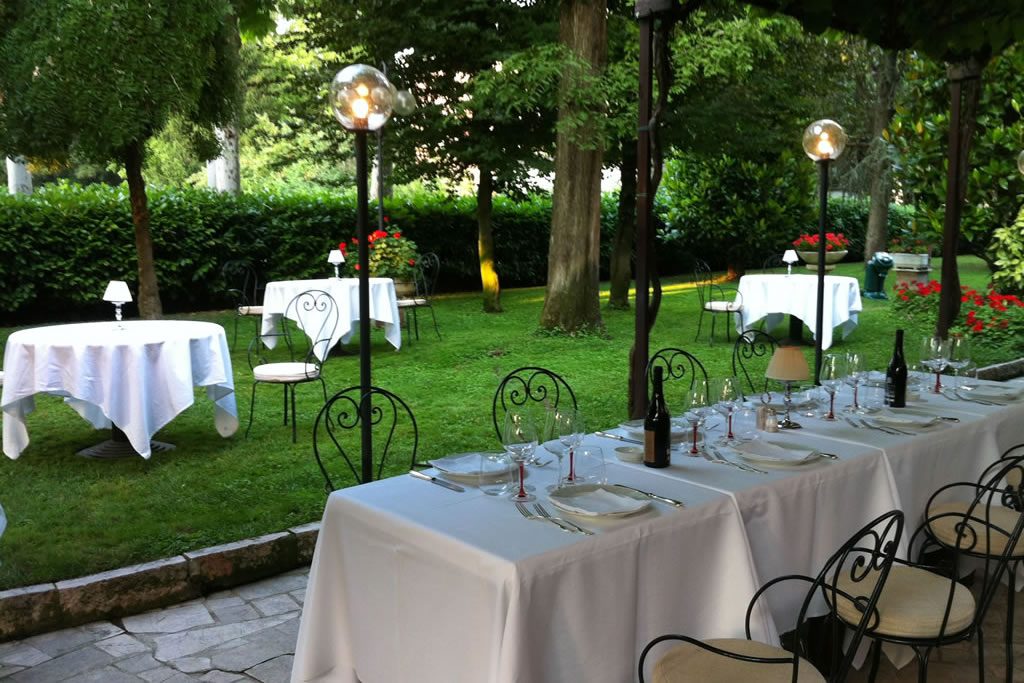 Tavoli apparecchiati nel giardino ombreggiato d'estate